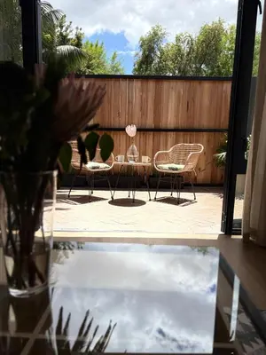 a patio with two chairs and a table and a vase at Protea Cottage Cozy & Private Studio in Claremont in Cape Town