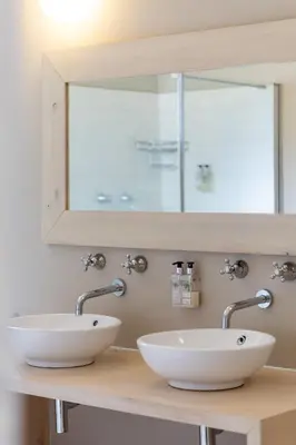 two white sinks on a counter with a mirror at Five Mountains Guest Farm & Spa in Wellington