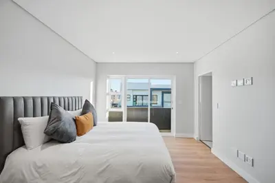a white bedroom with a large bed with pillows at Cape Signature Villa in Cape Town