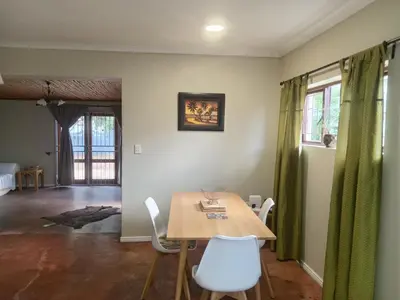 a dining room with a table and white chairs at Starfish Cottage in Kleinmond