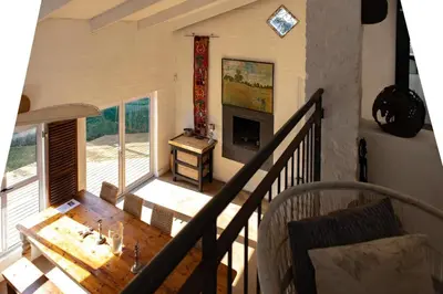 a living room with a wooden table and a fireplace at Joan's Sea Cottage in Pringle Bay