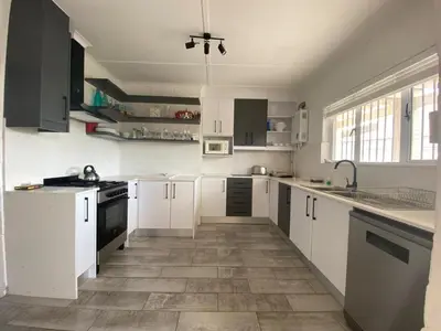 a kitchen with white cabinets and a tile floor at Joan's Sea Cottage in Pringle Bay