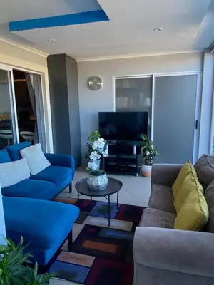 a living room with blue couches and a tv at Opulent Home Stay in Cape Town