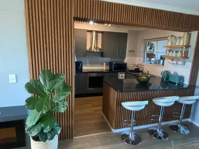 a kitchen with a counter and stools in a room at Opulent Home Stay in Cape Town