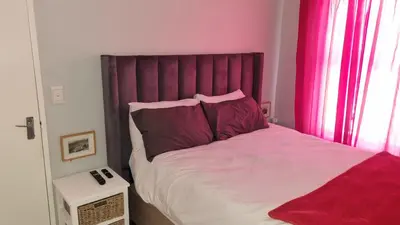 a bedroom with a large bed with a red headboard at Riley's Place in Cape Town