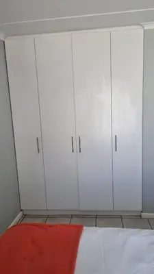 a bedroom with white cabinets and a red pillow at Riley's Place in Cape Town