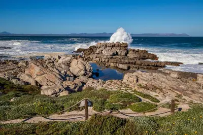 a wave crashing on the rocks at the ocean at Hermanus Homestay in Hermanus