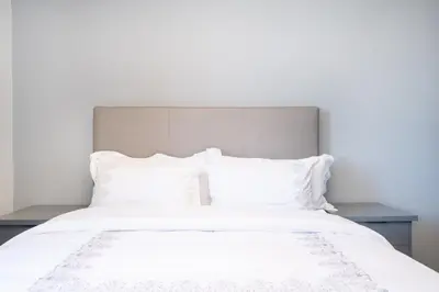 a white bed with white sheets and pillows at 311 Riverlands - Lux 2 Bedroom Apartment in Cape Town