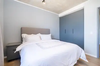 a bedroom with a white bed and a blue wall at 311 Riverlands - Lux 2 Bedroom Apartment in Cape Town
