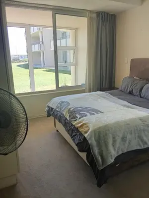 a bedroom with a bed and a large window at Spacious Beachfront 2bedroom apartment lagoon view in Cape Town