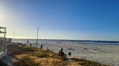a group of people sitting on a beach at Spacious Beachfront 2bedroom apartment lagoon view in Cape Town