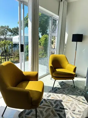 two yellow chairs in a living room with windows at Lux City Haven in Cape Town
