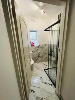 a bathroom with a toilet and a glass door at Lux City Haven in Cape Town