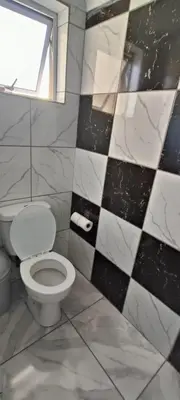 a bathroom with a toilet and a window at MAREE LODGe GUEST HOUSE BELLEVILLE in Bellville