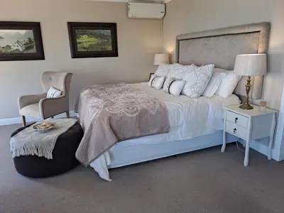 a bedroom with a white bed and a chair at Boutique Inn - Serenity in Gordonʼs Bay