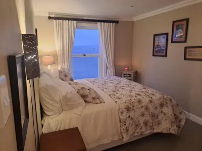 a bedroom with a bed with a view of the ocean at Boutique Inn - Whale Pod in Gordonʼs Bay