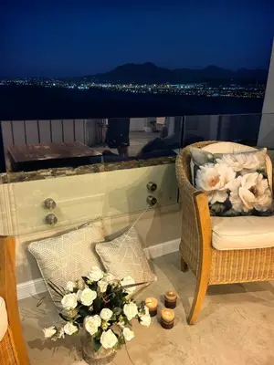 a balcony with a chair and flowers and candles at Boutique Inn - Whale Pod in Gordonʼs Bay