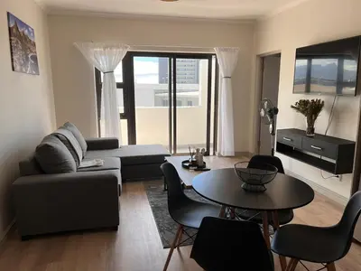 a living room with a couch and a table at EasyCapeTown - Bloubergstrand coastal apartment in Cape Town