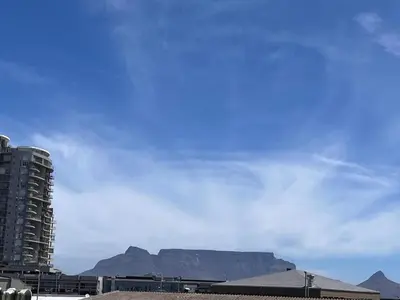 a view of a building and a mountain in the background at EasyCapeTown - Bloubergstrand coastal apartment in Cape Town
