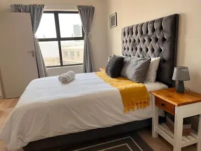 a bedroom with a large bed with a large window at EasyCapeTown - Bloubergstrand coastal apartment in Cape Town