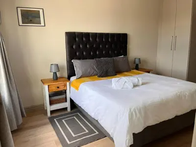 a bedroom with a large bed with a black headboard at EasyCapeTown - Bloubergstrand coastal apartment in Cape Town