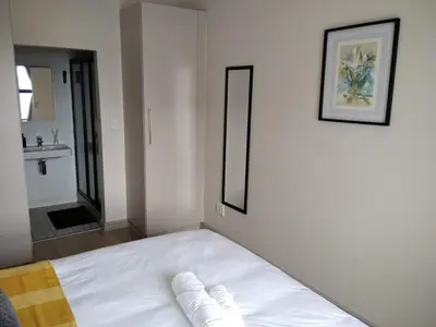 a white bed in a room with a bathroom at EasyCapeTown - Bloubergstrand coastal apartment in Cape Town