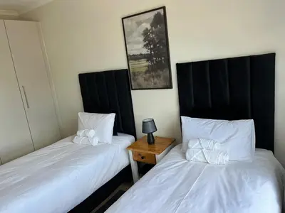 two beds sitting next to each other in a room at EasyCapeTown - Bloubergstrand coastal apartment in Cape Town