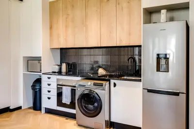 a kitchen with a refrigerator and a washing machine at Palmcrest Eden in Cape Town
