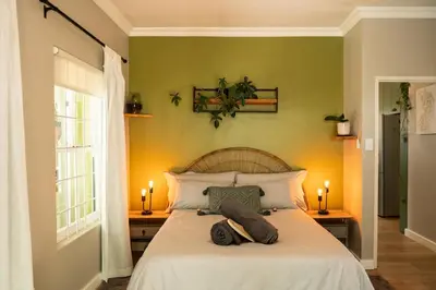 a bedroom with a bed with white sheets and two candles at Onrus Sunshine Beach Days in Hermanus
