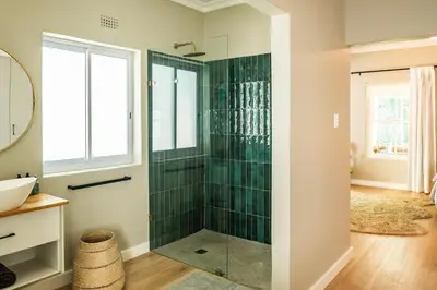 a bathroom with a shower with green tile at Onrus Sunshine Beach Days in Hermanus