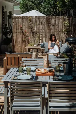 a woman sitting on a couch in a patio with a table at Onrus Sunshine Beach Days in Hermanus