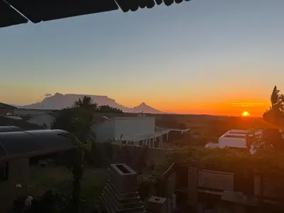 a sunset over a city with mountains in the background at Egret's Lookout in Cape Town