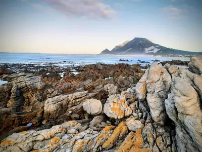 a group of rocks with a mountain in the background at Take A Break in Bettyʼs Bay