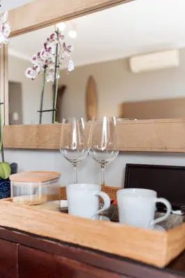 three wine glasses and cups on a wooden tray at Whale Away Guest House in Hermanus