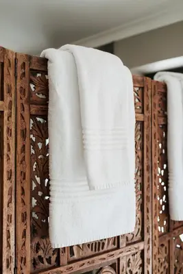 two white towels are hanging on a wooden rack at Whale Away Guest House in Hermanus