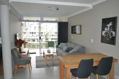 a living room with a couch and a table and chairs at Tyger Waterfront Penthouse Duplex Apartment in Tyger Valley
