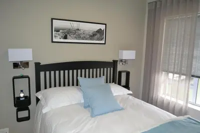 a bedroom with a bed with white sheets and blue pillows at Tyger Waterfront Penthouse Duplex Apartment in Tyger Valley