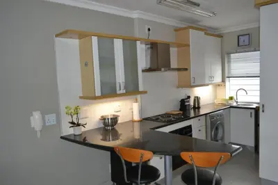 a kitchen with a counter and chairs in it at Tyger Waterfront Penthouse Duplex Apartment in Tyger Valley