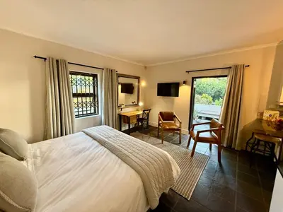 a bedroom with a bed and a desk and a table at 1 at Huis Piron in Stellenbosch
