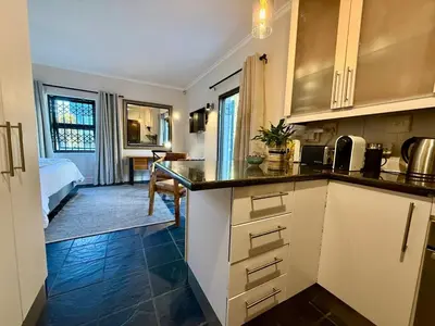 a kitchen with a counter and a room with a bed at 1 at Huis Piron in Stellenbosch