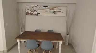 a table with four chairs and a painting on the wall at Tin Home 88 in Cape Town
