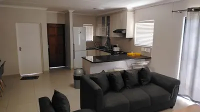 a living room with a couch and a kitchen at Tin Home 88 in Cape Town