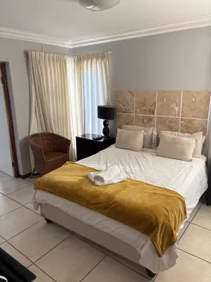 a bedroom with a large bed and a chair at Christal Villa A33 in Cape Town
