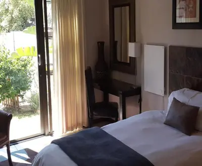 a bedroom with a bed and a desk and a window at Christal Villa A33 in Cape Town
