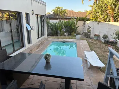 a patio with a table and a swimming pool at Christal Villa A33 in Cape Town