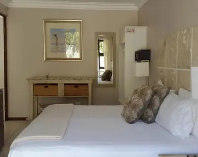 a bedroom with a large white bed and a mirror at Christal Villa A33 in Cape Town