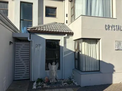 a white house with a door with a statue in it at Christal Villa A33 in Cape Town