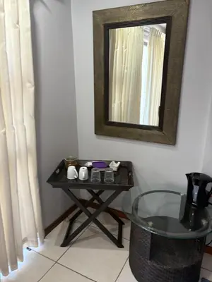a table with a mirror and a table with a chair at Christal Villa A33 in Cape Town