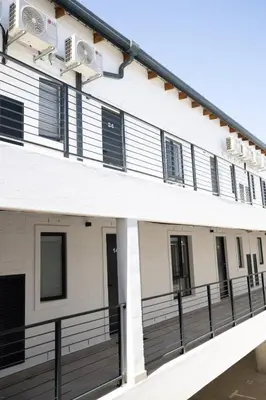 an exterior view of a white building with black railing at 10 at The Alxndr - Stellenbosch Central in Stellenbosch