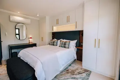 a bedroom with a large white bed and a mirror at 10 at The Alxndr - Stellenbosch Central in Stellenbosch